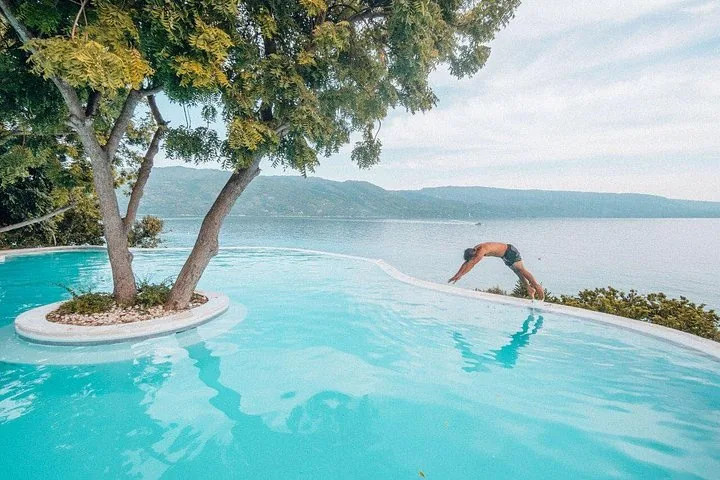 Man diving into an infinity pool with an ocean view in the background.