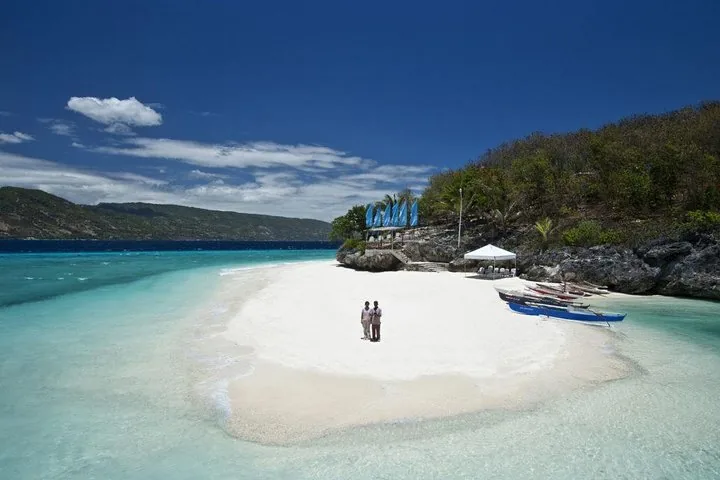Couple standing on a pristine white sandbar surrounded by turquoise water.